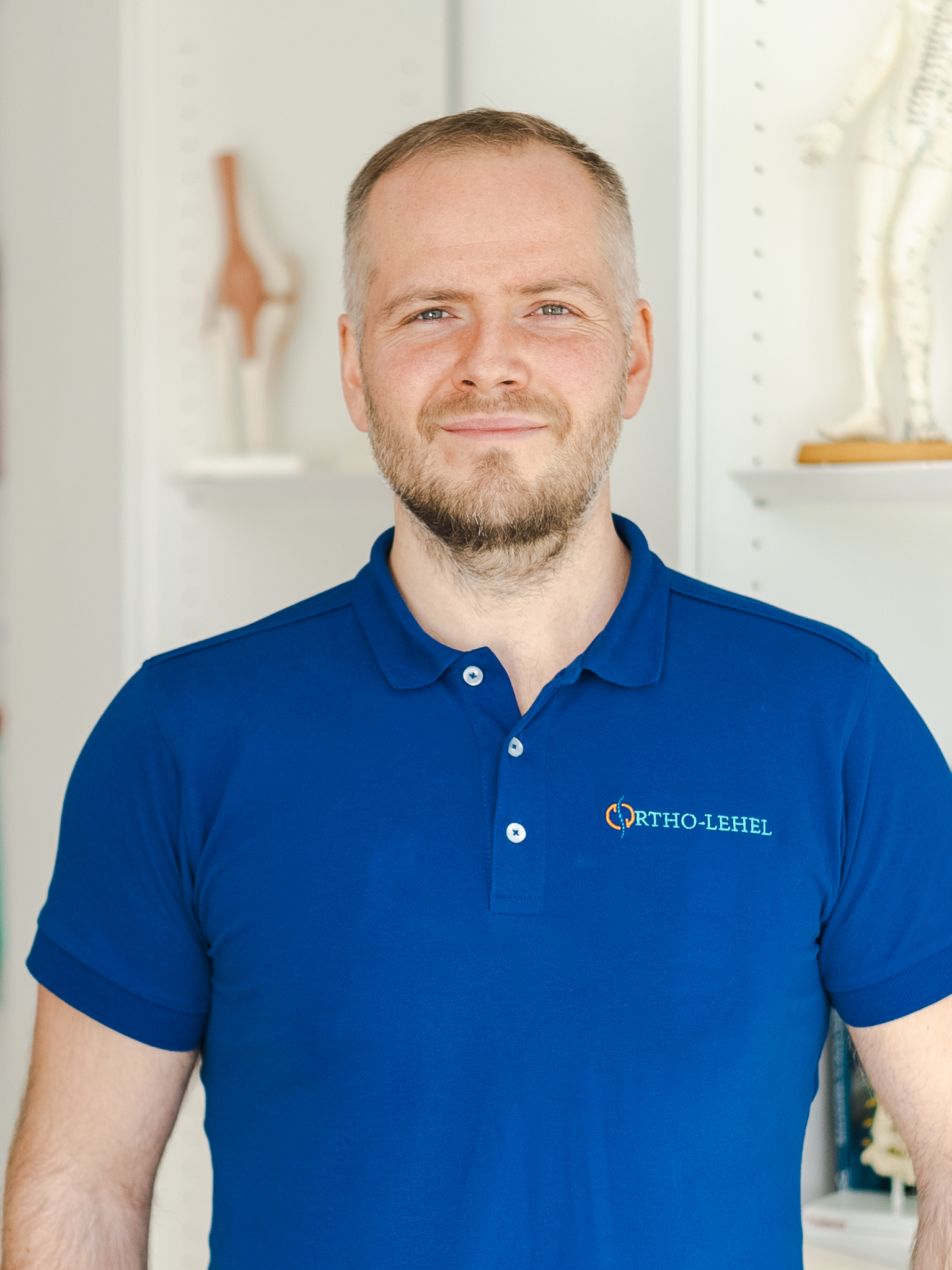 Orthopäde München, ein professioneller Orthopäde namens Dr. Michael Wunderlich in einem blauen Hemd mit einem Logo von Ortho-Lehel auf der linken Seite.